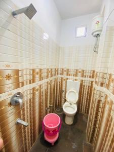 La salle de bains est pourvue de toilettes et d'un seau rose. dans l'établissement Seven star, à Indore