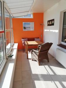クックスハーフェンにあるFerienwohnung-2-im-Sahlenburger-Ferienhausのオレンジ色の壁のバルコニー(テーブル、椅子付)