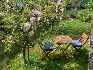 uma mesa de piquenique e cadeiras ao lado de uma árvore com flores cor-de-rosa em B&B Biel-Brügg em Brügg