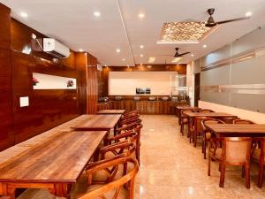 una sala da pranzo con tavoli e sedie in legno di Hotel The Tirath View a Haridwār
