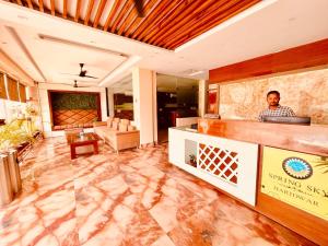 Un uomo in piedi dietro un bancone in una hall di Hotel The Tirath View a Haridwār