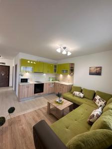 a living room with a green couch and a kitchen at Апартамент "ИЛИЕВИ" in Obzor
