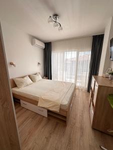 a bedroom with a bed and a large window at Апартамент "ИЛИЕВИ" in Obzor