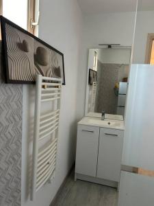 een witte badkamer met een wastafel en een spiegel bij Longère sur Loire 