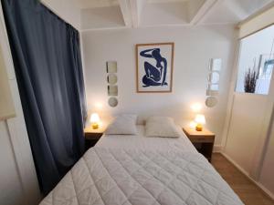 een slaapkamer met een wit bed en 2 nachtkastjes bij Résidence Cassiopée - maeva Home - Studio 4 personnes - Budget 53 in Arâches-la-Frasse