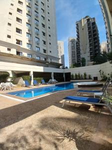 una piscina con tumbonas azules y edificios en Flat Completo em Hotel 4 estrelas no Jardins! Com piscina, Jacuzzi, Sauna e academia!, en São Paulo
