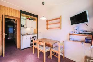 eine Küche mit einem Tisch und Stühlen sowie einem Kühlschrank in der Unterkunft Résidence Antarès - maeva Home - Studio 4 Personnes - Budget 62 in Flaine