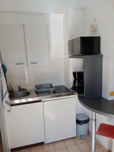 uma cozinha com armários brancos e um balcão preto em Les Hortensias em Challans