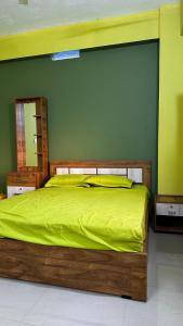 a bedroom with a wooden bed with a green wall at VALIYAVEETTIL INN in Irikkūr