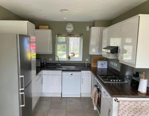 uma cozinha com armários brancos e um relógio na parede em Beautiful Home in Dorset em Winterborne Kingston