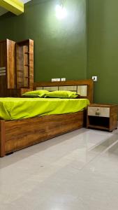 een slaapkamer met een houten bed met een groene muur bij VALIYAVEETTIL INN in Irikkūr