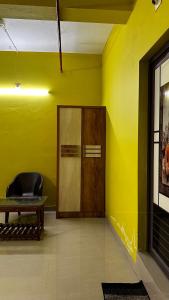 a yellow room with a wooden door and a chair at VALIYAVEETTIL INN in Irikkūr