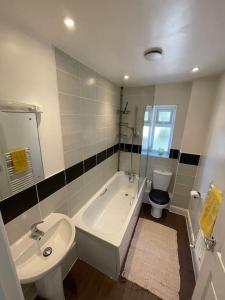 uma casa de banho com um lavatório, uma banheira e um WC. em Beautiful Home in Dorset em Winterborne Kingston