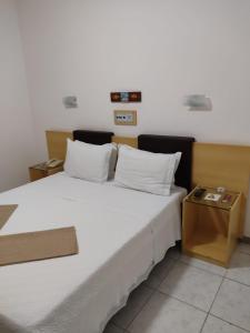 Un dormitorio con una gran cama blanca y una mesa en Pousada do Garimpo, en Diamantina