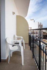 2 sillas blancas en un balcón con vistas en Hostal Alicante, en San Antonio
