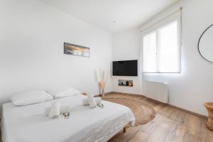 a white bedroom with a white bed and a television at Appartement Blanqui - Welkeys in La Seyne-sur-Mer