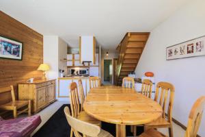 uma cozinha e sala de jantar com uma mesa de madeira e cadeiras em Résidence Le Château de Crans - maeva Home - Appartement Pièces - Budget 52 em Flaine
