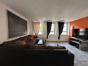 ein Wohnzimmer mit einem Sofa und einer Tafel an der Wand in der Unterkunft Appart Pro & Famille in Verdun-sur-Meuse