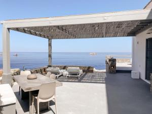 a patio with a table and chairs and the ocean at Cliff Villa in Sarakíniko