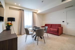 sala de estar con mesa, sillas y sofá rojo en I Due Mori - Luxury Rooms en Giardini Naxos