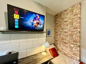 a living room with a flat screen tv on a brick wall at Limpenny Studio - Cityscape Cozy Corner in Nottingham