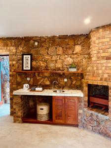 une cuisine en pierre avec un évier et un mur en pierre dans l'établissement Casa da Namaacha, à Maputo