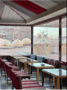 un restaurante con mesas y sillas y una gran ventana en مخيم الانيق, en Wadi Rum