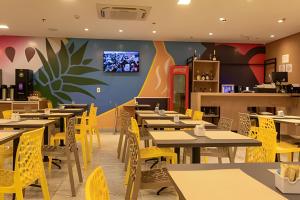 a dining room with tables and yellow chairs at Hosts BR-Flat Fit Transamérica Boa Viagem s/ taxa in Recife