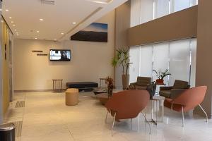a lobby with chairs and a tv on the wall at Hosts BR-Flat Fit Transamérica Boa Viagem s/ taxa in Recife