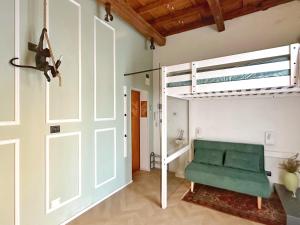 um quarto com uma cadeira verde e uma cama alta em Loft Biagio50 in Centro em Ferrara