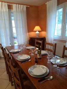 een tafel met borden en glazen en een fles wijn bij LA CONFRERIE à MEURSAULT au CŒUR DE LA BOURGOGNE in Meursault