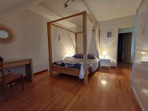 a bedroom with a canopy bed and a wooden floor at LA CONFRERIE à MEURSAULT au CŒUR DE LA BOURGOGNE in Meursault