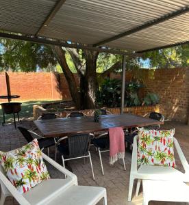 a wooden table and chairs under an umbrella at Lielies Guesthouse in Parys