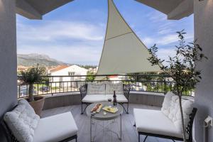 - un balcon avec des chaises blanches, une table et une voile dans l'établissement Florami Apartment, à Kaštela