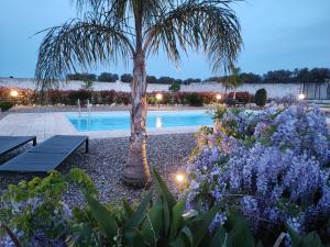 una palmera y una piscina con flores en Villa Marinezzi, en Mesagne