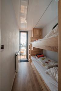 Habitación con 2 literas y pasillo. en Hausboot Püntenel - stationär - Traumhafte Ferienwohnung AUF dem Wasser en Kinrooi