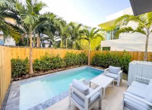a swimming pool in a backyard with a fence and palm trees at Coconut Groove Green s VIlla in Miami