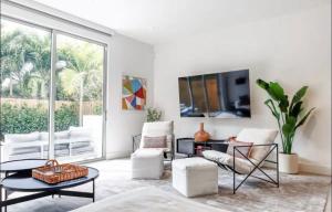 a living room with white furniture and a large window at Coconut Groove Green s VIlla in Miami