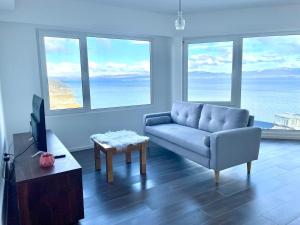 a living room with a couch and a tv and windows at Turek Residences in Ushuaia