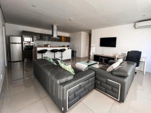 a living room with a leather couch and a kitchen at Sky Cabins Apartments in Windhoek