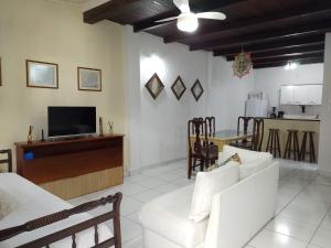 a living room with white furniture and a tv at Apartamento no Centro de Búzios in Búzios