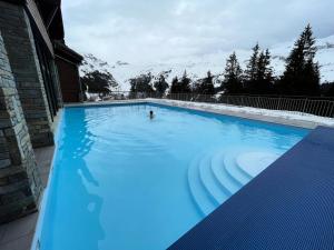 a person swimming in a large blue swimming pool at Résidence Les Terrasses d'Eos - maeva Home - Appartement 2 pièces 4 personnes - Prestige MAE-6034 in Arâches-la-Frasse +21 photos