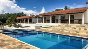 a swimming pool in front of a house at Sítio com Piscina e Área de Lazer Completa in Porangaba