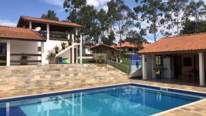 an image of a swimming pool in front of a house at Sítio São Luiz: Experimente Autenticidade Rústica in Porangaba