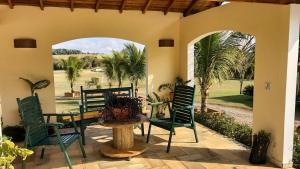 a patio with green chairs and a table and a view of a field at Sítio com Piscina e Área de Lazer Completa in Porangaba
