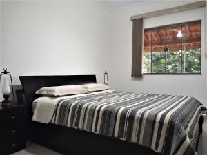 a bedroom with a bed with a striped blanket and a window at Sítio com Piscina e Área de Lazer Completa in Porangaba +127 photos