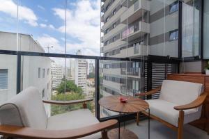 einen Balkon mit Stühlen, einem Tisch und einem großen Fenster in der Unterkunft BHomy Pinheiros Estiloso e jovem V1014 in São Paulo