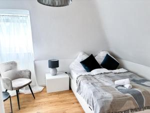 1 dormitorio blanco con 1 cama y 1 silla en ThinkPink! Apartment Ennepetal * Sehr modern * Top Lage en Ennepetal