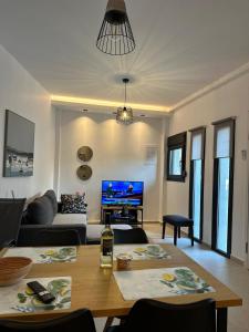 a living room with a table and a tv at K.G apartment in Pefkohori