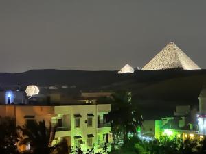 einen Blick auf die Pyramiden einer Stadt in der Nacht in der Unterkunft Pyramids Era View in Kairo